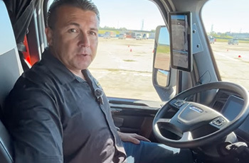 Man in the driver's seat of a Freightliner cab using MirrorCam.